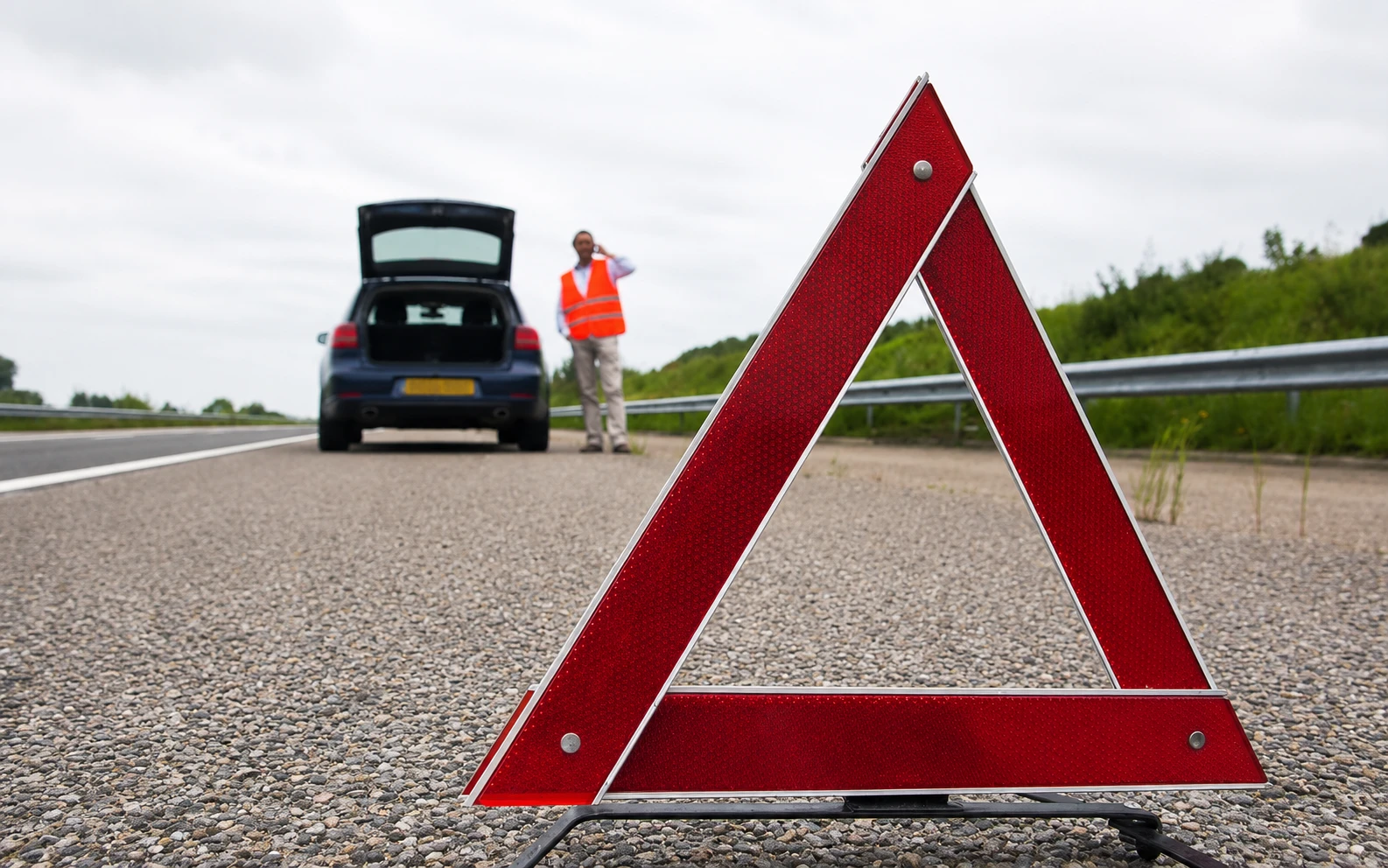 Triangle de signalisation derrière une voiture en panne sur la bande d'arrêt d'urgence